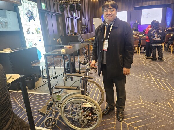 ▲로보라이프 전창훈 대표가 수동 휠체어에 손쉽게 장착하면 전동 휠체어로 바꿔주는 휠체어 동력보조장치를 소개하고 있다. 이 회사는 반자율 침상 888토토도 개발해 이번 전시회에 알리고 있다. (사진=888토토신문)